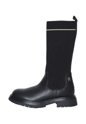 Stivali neri alti fino al ginocchio con parte inferiore in pelle e parte superiore in maglia, con logo con accento dorato e suola testurizzata per una presa migliore.