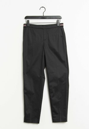 Black tailored trousers with side pockets and striped waistband detail, hanging on a black clip hanger against a white background.