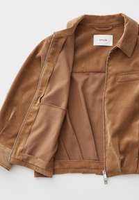 Brown corduroy jacket with open silver zipper, folded collar, chest pocket, and visible inner lining showing brand label "OPUS".