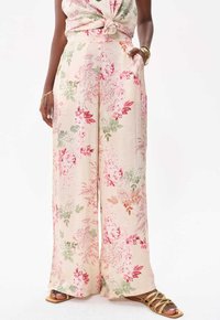 Blommigt mönstrade vida byxor i mjuk creamfärgad tyg, med rosa, gröna och röda botaniska mönster. Inkluderar sidfickor och en avslappnad passform.