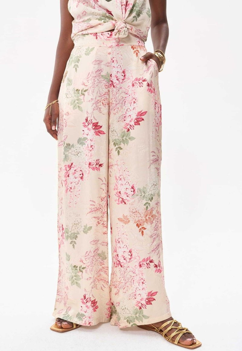 Blommigt mönstrade vida byxor i mjuk creamfärgad tyg, med rosa, gröna och röda botaniska mönster. Inkluderar sidfickor och en avslappnad passform.