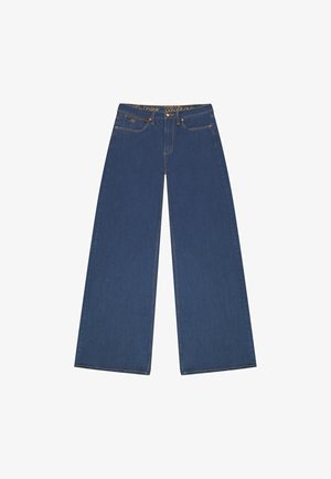 Wide-leg denim trousers in dark blue. Features a high waistband with logo detail, five pockets, and yellow stitching along the seams.