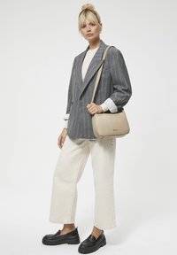 Szary marynarka w prążki na beżowym swetrze, w połączeniu z kremowymi spodniami typu wide-leg i czarnymi platformami loafersami. Beżowa torba na ramię z detalem logo.