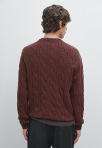 Bordeaux kabelgebreide trui met een gestructureerd patroon, ronde hals en geribbelde manchetten, gezien vanaf de achterkant, met een ontspannen pasvorm.