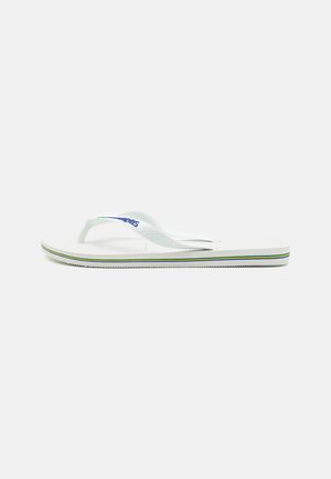 Hvide flip-flops med en tekstureret fodseng, slanke stropper og en flerfarvet accentlinje på sålen. Har logo på stroppen.