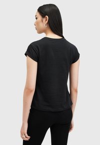 Camiseta negra de manga corta con puños enrollados, hecha de algodón suave, con un corte relajado y una textura sutil.