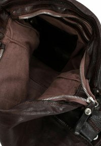 Innenansicht einer braunen Ledertasche mit mehreren Fächern, ausgestattet mit einem dunklen Stofffutter und silbernen Reißverschlüssen mit schwarzen Akzenten.