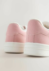 Jasnoróżowe sneakersy o zamszowej strukturze, biała gumowa podeszwa i miękka wykładzina z polarowego materiału w kołnierzu i języku. Subtelne detale w szyciu.