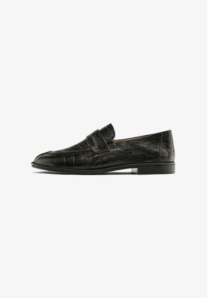Black loafers with a crocodile leather texture, featuring a prominent strap across the instep, displayed against a white background.