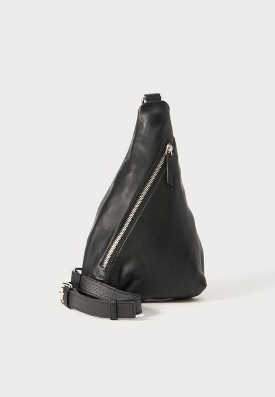 Sac en cuir noir en forme triangulaire, avec une poche zippée sur le côté et une bandoulière texturée. Finition lisse avec des accents en métal argenté.