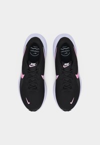 Ζευγάρι μαύρα αθλητικά παπούτσια Nike με ροζ λογότυπα swoosh και λευκές σόλες, από πάνω, σε λευκό φόντο.