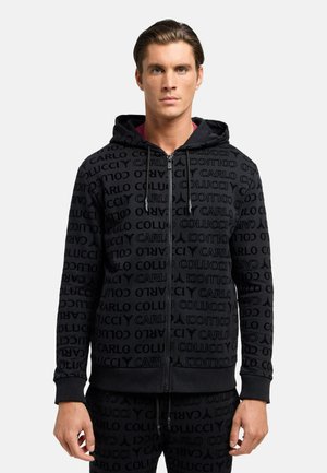 Black zip-up hoodie with embossed brand names in a repeating pattern. Features a drawstring hood and ribbed cuffs. Casual fit.