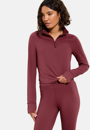 Vinröd sportpullover med kvartszipp, långärmad och med tumhål, kombinerad med matchande figurnära leggings. Mjuk, stretchig tyg.