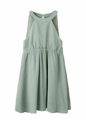 Robe sans manches vert clair en tissu texturé, taille froncée, encolure halter et panneaux en dentelle mesh sur les côtés.