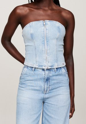 Mørkhudet person iført en lyseblå strapless denim top med lynlås foran og matchende lyseblå denim jeans.