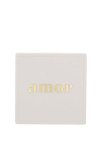 Fyrkantig keramisk platta i mjuk grå färg med ordet "amor" i glänsande guldtext, med en subtil präglad kant runt kanterna.