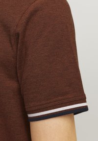 Korte mouwen bruine polo shirt van textuurstof, met een contrasterende navy en witte gestreepte manchet.