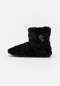 Schwarzer Plüschschlupfstiefel mit schichtweiser Textur, runder Zehenform und einer Schleifenakzent auf der Seite. Weiches Material und knöchelhohes Design.