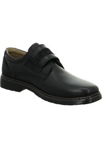 Scarpa nera in pelle con finitura liscia, dotata di una fascia in velcro e punta arrotondata. Suola robusta in gomma con un sottile motivo di battistrada.