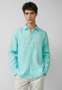 Camicia a maniche lunghe turchese in lino leggero. Presenta un colletto button-down e una finitura testurizzata sottile con bottoni chiari.