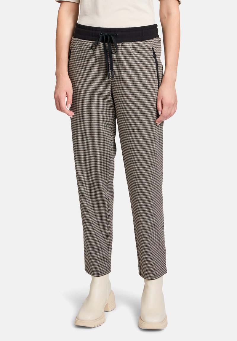 Pantalons à carreaux noir et blanc avec une taille élastique noire, dotés d'un cordon de serrage et de poches zippées sur les côtés. Texture de tissu lisse.