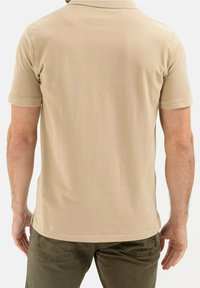 Khaki polo z teksturowanej tkaniny, krótki rękaw i luźny krój. Posiada klasyczny kołnierz oraz wzmocnione boczne rozcięcia dla wygody.