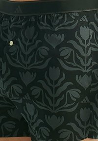 Černé boxerky s tónovým květinovým vzorem, vybavené elastickým pasem s malým logem a knoflíkovým zapínáním.