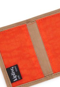 Orange stofpung med beige accenter, der har syninger og et sort mærke med teksten "Kipling Live Light."