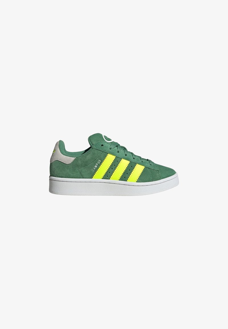 Zapatillas de ante verde con tres franjas amarillas llamativas, una suela de goma blanca y un acento gris en el talón. Punta redonda con diseño de cordones.