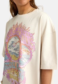 Short sleeve beige t-shirt featuring a colorful graphic design with flames, waves, flowers, and the text "Natural Mystic" in bold lettering.