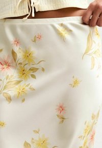 Květinová sukně z lehké krémové látky s žlutými a růžovými květinovými vzory, měkkou texturou, hladkým povrchem a elastickým pasem.