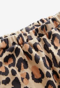 Tissu à imprimé léopard avec des nuances de noir, brun et beige. Se compose d'une taille élastique et d'un matériau doux et texturé.