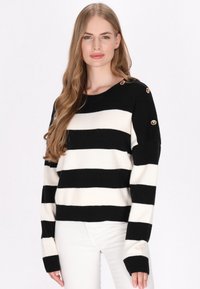 Maglione a strisce bianche e nere con scollatura tonda, texture a maglia, vestibilità oversize e dettagli con bottoni dorati sulla spalla.