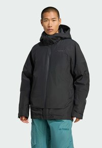 Czarna wodoodporna kurtka z zamkiem błyskawicznym, regulowanym kapturem i elastycznymi mankietami. Z przodu znajduje się logo "TERREX" w kontrastowym kolorze.