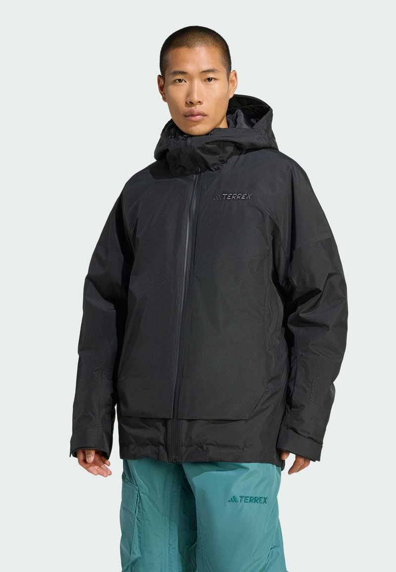 Czarna wodoodporna kurtka z zamkiem błyskawicznym, regulowanym kapturem i elastycznymi mankietami. Z przodu znajduje się logo "TERREX" w kontrastowym kolorze.