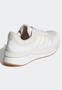 Baskets de sport blanches en mesh et matériau synthétique. Elles présentent une tige texturée avec trois bandes, un col rembourré et une semelle en caoutchouc.