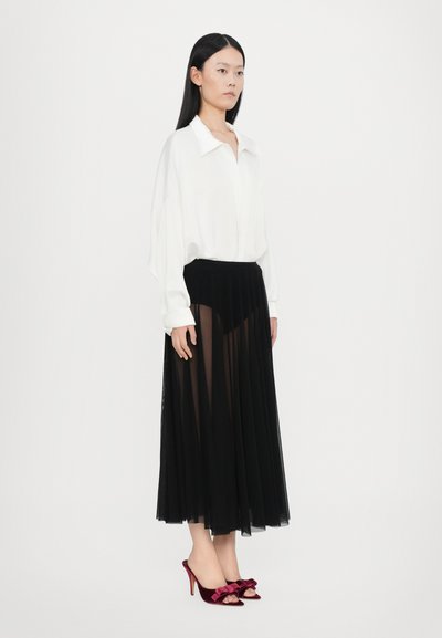 Blusa blanca con cuello, falda negra de gasa plisada, zapatos de tacón fucsias con detalle de lazo. Diseño simple y elegante con colores contrastantes.