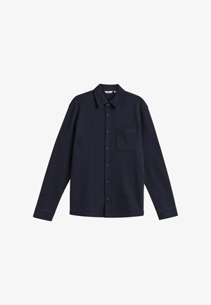 Chemise à manches longues bleu marine en tissu texturé, dotée d'un col, d'une fermeture à boutons sur le devant et d'une poche poitrine unique.