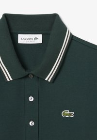 Groene poloshirt met een geribde kraag voorzien van witte en grijze strepen, twee knopen en een klein geborduurd krokodillenlogo.