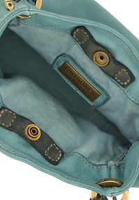 Interno di una borsa a mano in pelle blu chiaro con una consistenza morbida, dotato di una placca metallica del marchio, accenti neri a contrasto e dettagli di cucitura.