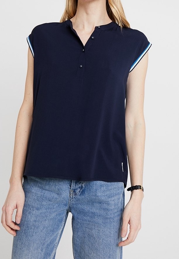 Top però a maniche corte di colore blu navy con colletto, caratterizzato da due bottoni frontali e dettagli blu a contrasto sulle maniche. Tessuto leggero e vestibilità rilassata.