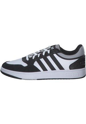 Zwart-witte sport sneaker met een ronde neus, stoffen bovenkant, drie zwarte strepen en rubberen zool; heeft een vetersluiting aan de voorkant en een gevoerd kraagje.