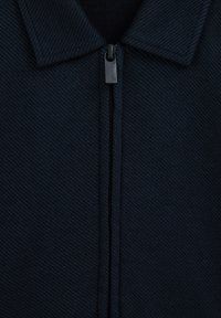 Jachetă albastru închis cu fermoar, guler cu rever și țesătură texturată cu dungi diagonale și închidere centrală cu fermoar.