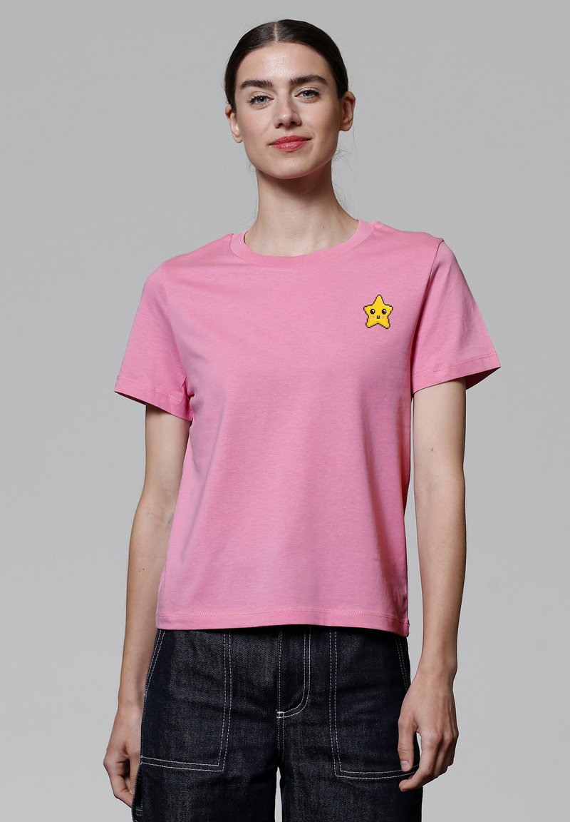 Pinke Baumwoll-T-Shirt mit Rundhalsausschnitt und kurzen Ärmeln, versehen mit einem gelben Stern-Patch auf der linken Brust.