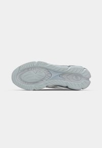 Ljusgrå sneakersula med ett texturerat mönster, med vågformade spår och en central stöddesign. Hållbart gummi material.