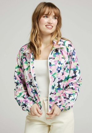 Veste zippée à motifs floraux avec une base blanche ornée de motifs roses, verts et bleus. Le matériau semble léger avec des poignets et un ourlet élastiques.