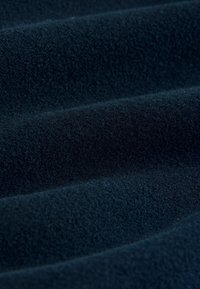 Țesătură de culoare albastru închis, cu o suprafață moale și texturată, care prezintă ușoare pliuri și unde, creând un aspect confortabil și luxuriant.
