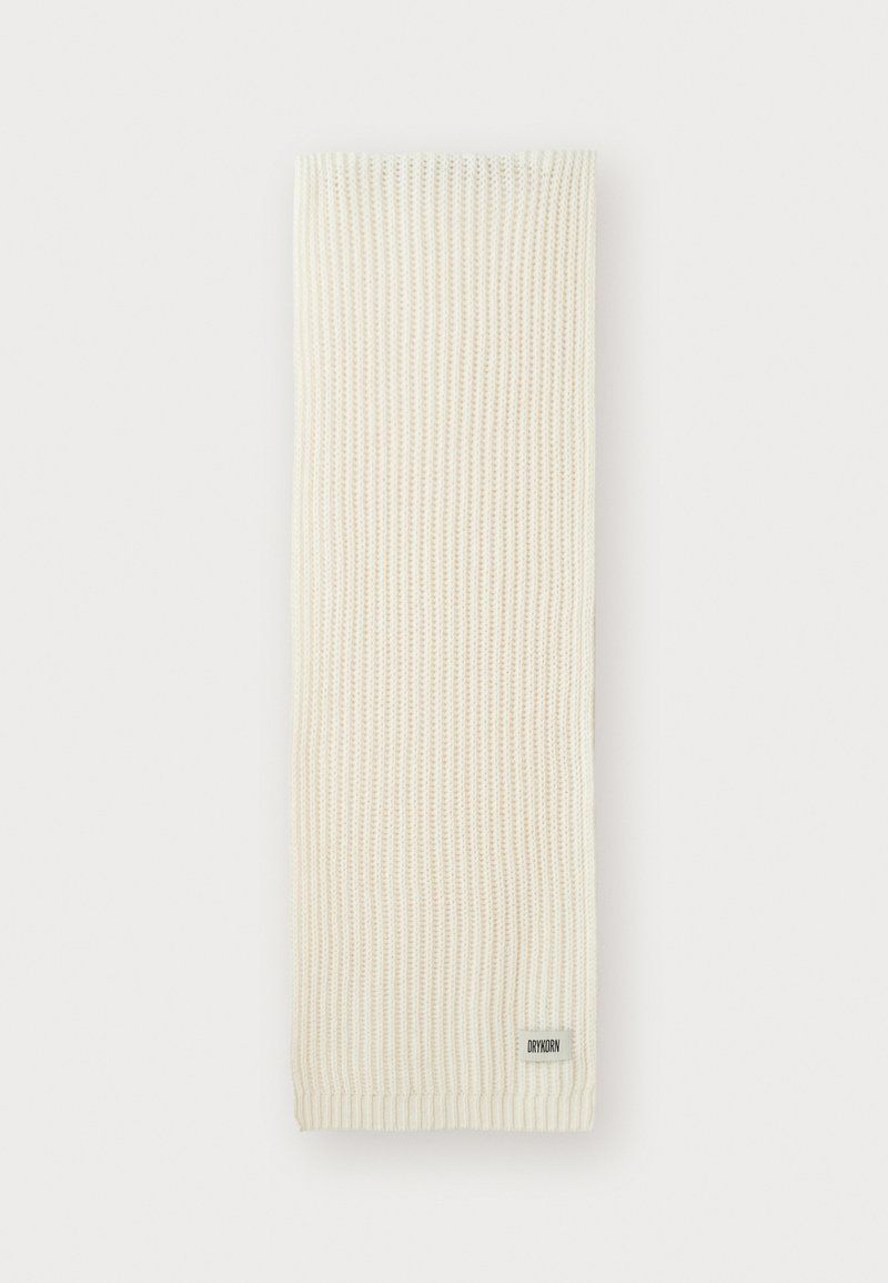 Sciarpa lavorata a maglia color crema con una texture a coste e un piccolo etichetta con il marchio. Forma rettangolare lunga, ideale per essere avvolta o sovrapposta.