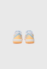 Sport shoes featuring a white upper with light blue and orange accents, textured heel, and a rubber sole for grip.