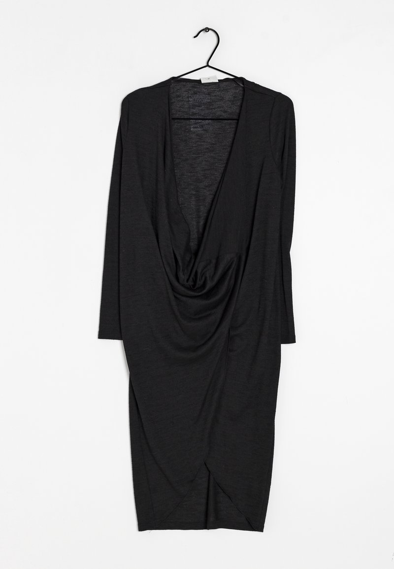 Robe noire drapée sur un cintre, avec manches longues, un profond décolleté en V et un tissu froncé sur le devant avec un ourlet effilé.